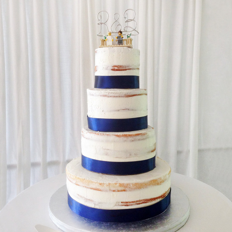 Свадебный торт с синей лентой и фигурками молодоженов