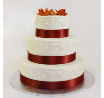 Свадебный торт с красной лентой и осенней листвой