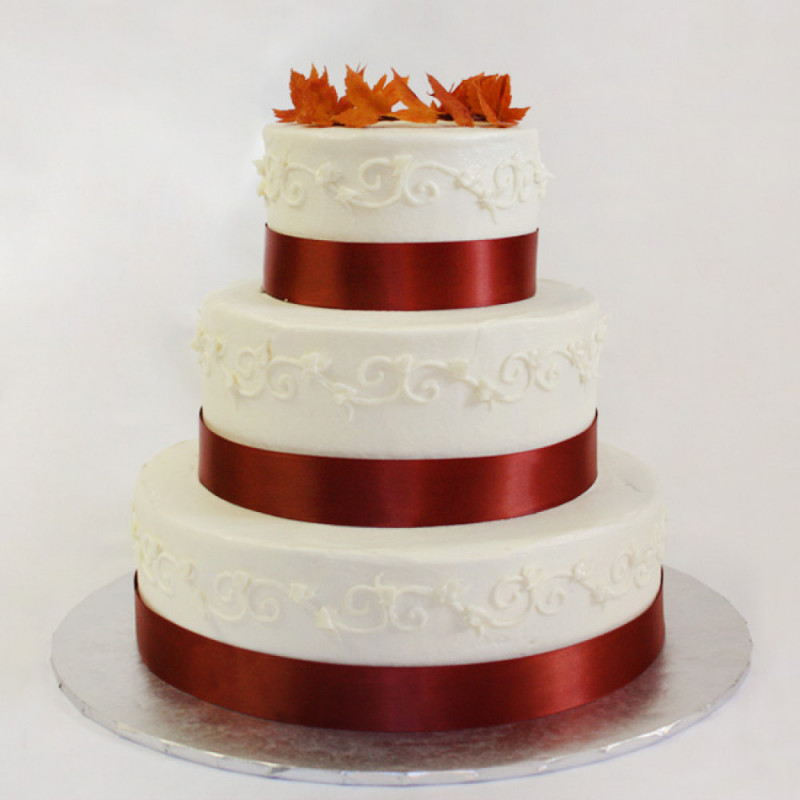 Свадебный торт с красной лентой и осенней листвой